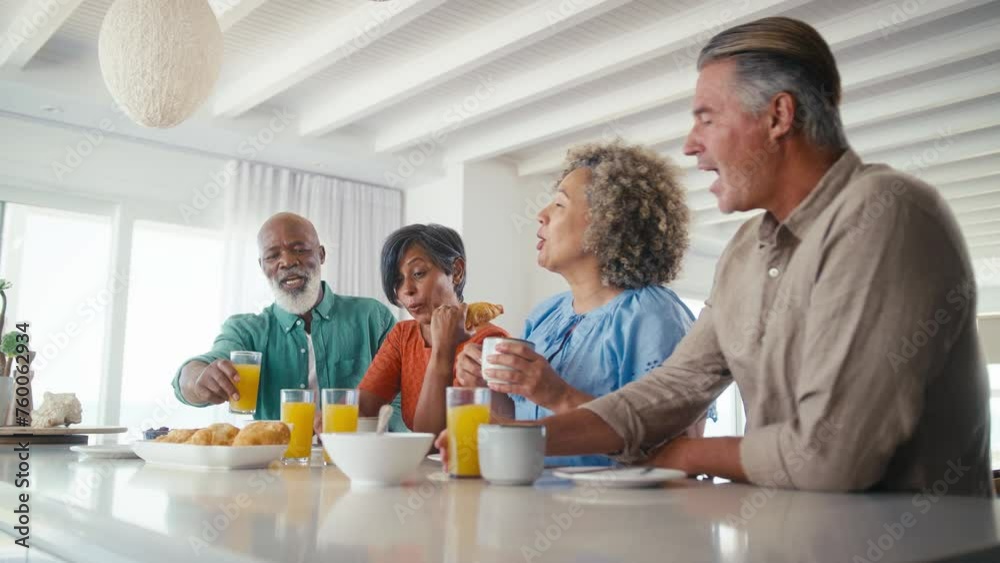 Group of mature friends on vacation or at home eating breakfast together - shot in slow motion Group of mature friends on vacation or at home eating breakfast together - shot in slow motion