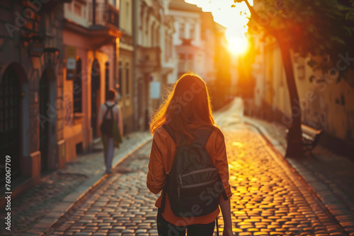 Girl backpacking travelling through old city streets against the backdrop of the setting sun, tourism