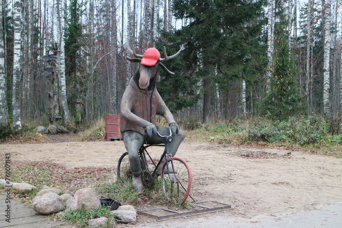 moose on bicycle funny garden sculpture, forest landscape