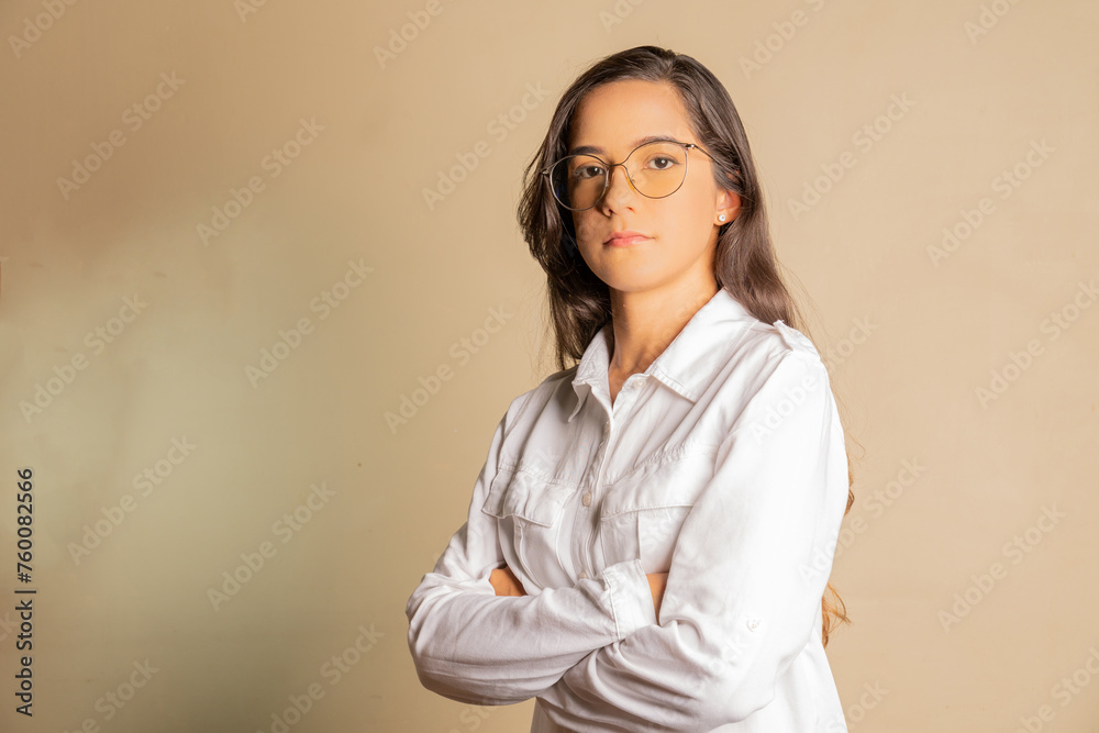 young female student looking confidently ahead crossing her arms, dressed casually in a white shirt young female student looking confidently ahead crossing her arms, dressed casually in a white shirt