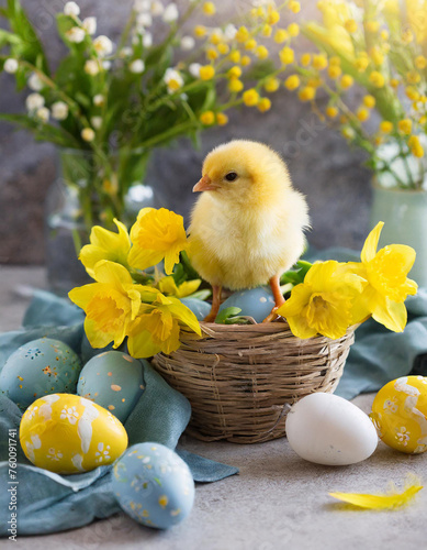 A cute little chicken on the table, Easter eggs, Easter celebration, yellow flowers, spring. © Naji