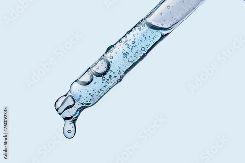 Cosmetic dropper pipette with drop transparent texture  on blue background photo