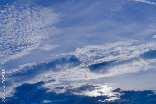 Niebo lekko zachmurzone, częściowo pokryte białymi chmurami, zza których widać błękit nieboskłonu.
