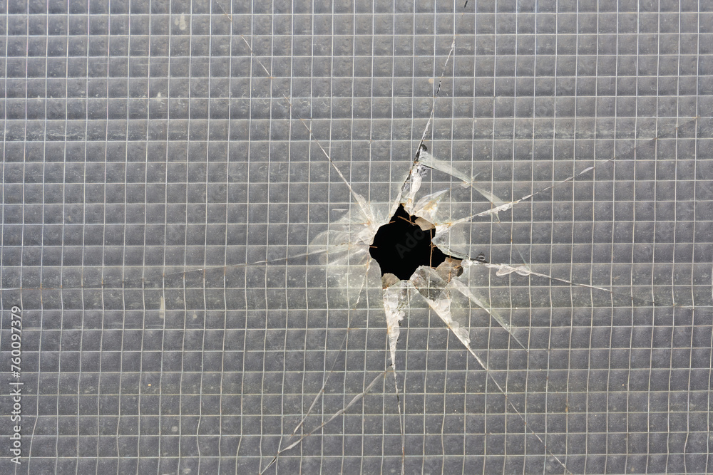 Loch in einem zerstörten Fenster aus Sicherheitsglas - obrazy, fototapety, plakaty 