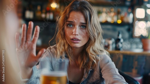 Young Caucasian woman turning down a beer offered to her, concept of sobriety and recovery from alcoholism/addiction