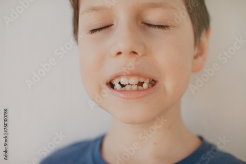 A preschool boy in a blue T-shirt on a light background shows a thumbs up