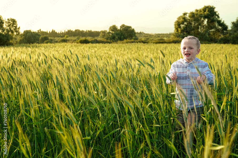 Young child having fun running in meadow with sunset. Happy kid playing outside in nature field Young child having fun running in meadow with sunset. Happy kid playing outside in nature field