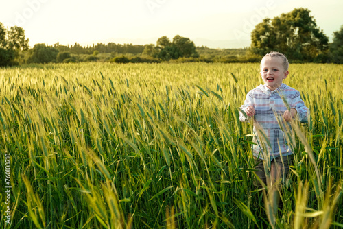 Young child having fun running in meadow with sunset. Happy kid playing outside in nature field