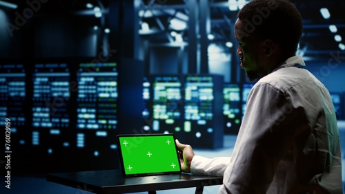 Experienced admin auditing supercomputer performance trends. Skilled employee using green screen tablet to spot high tech facility operational issues causing servers to slow down