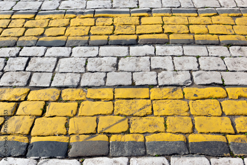 Cobblestone pavement painted with white and yellow stripes, pedestrian crossing, brick road - background is blurred, bokeh, selective focuse