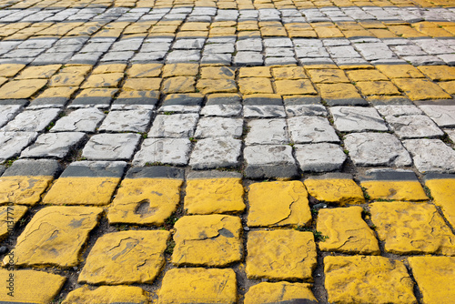 Obraz na płótnie Cobblestone pavement painted with white and yellow stripes, pedestrian crossing, brick road - background is blurred, bokeh, selective focuse w salonie