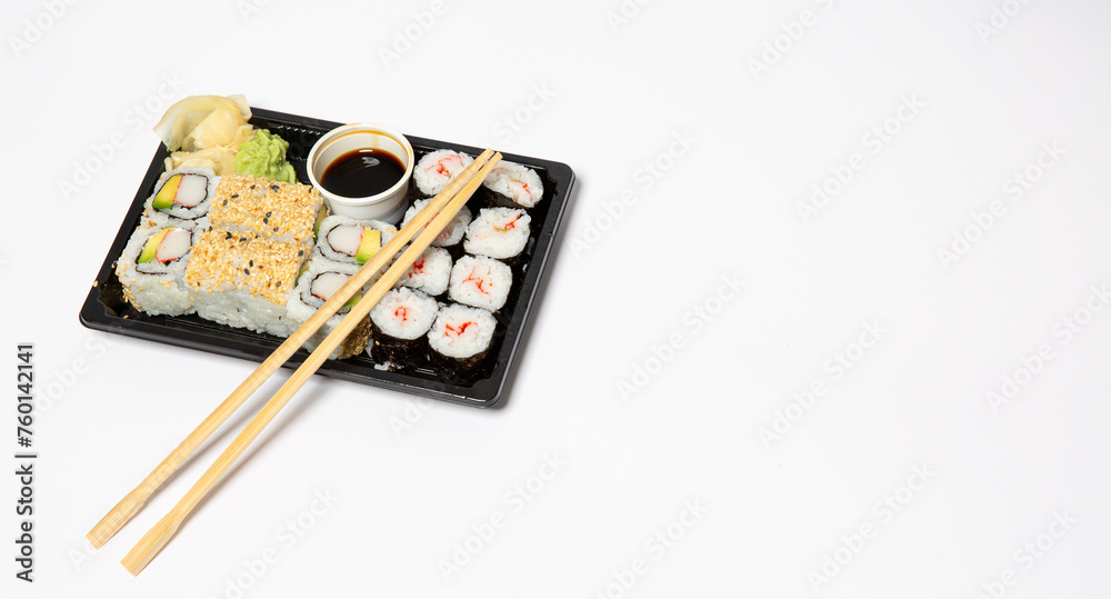 Sushi to go in a black takeaway box with wooden chopsticks on white background Sushi to go in a black takeaway box with wooden chopsticks on white background