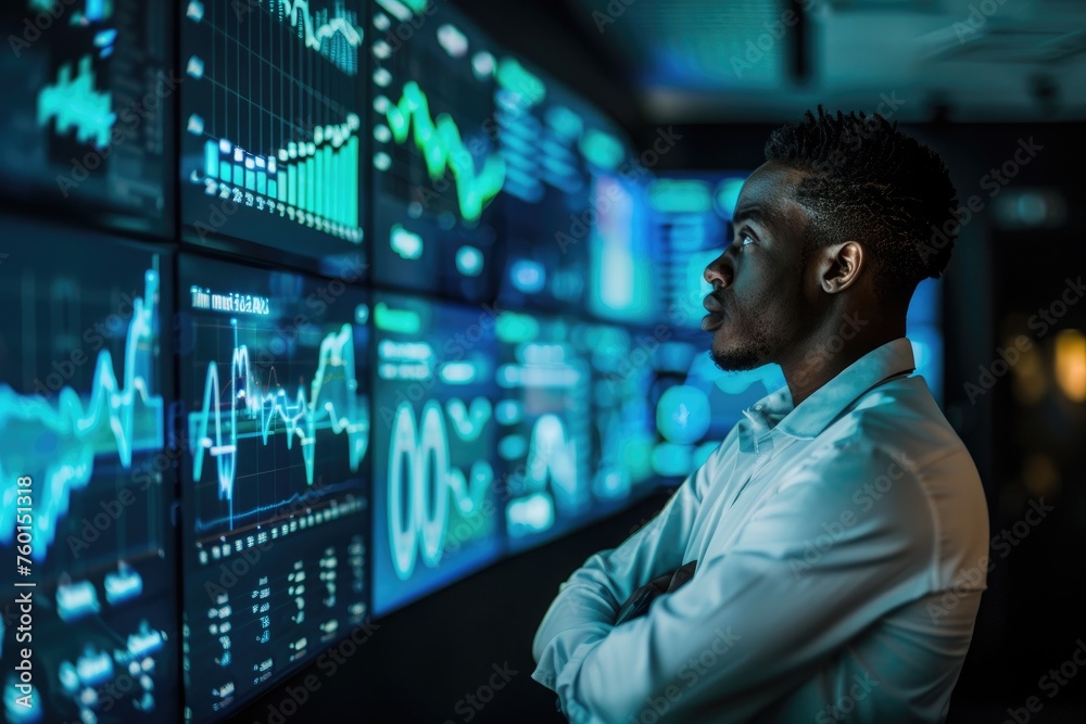 Man reviewing data on multiple screens. Man reviewing data on multiple screens.