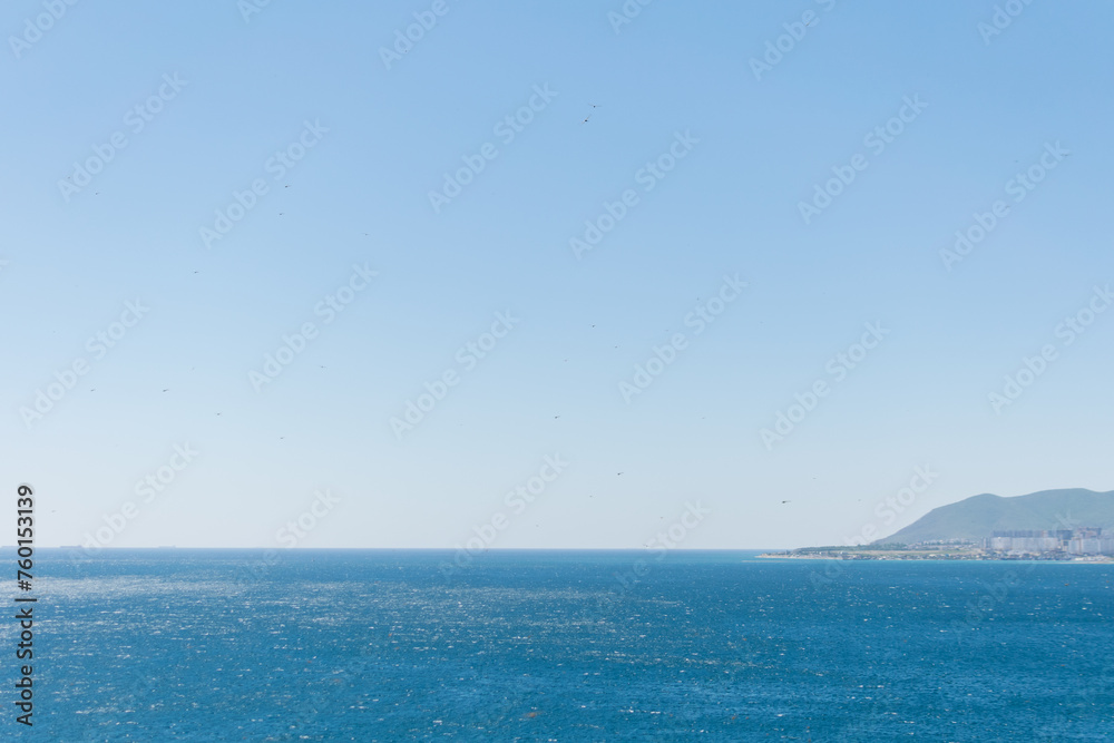 Sea horizontal landscape - blue sky, blue sea, mountain hills on the horizon