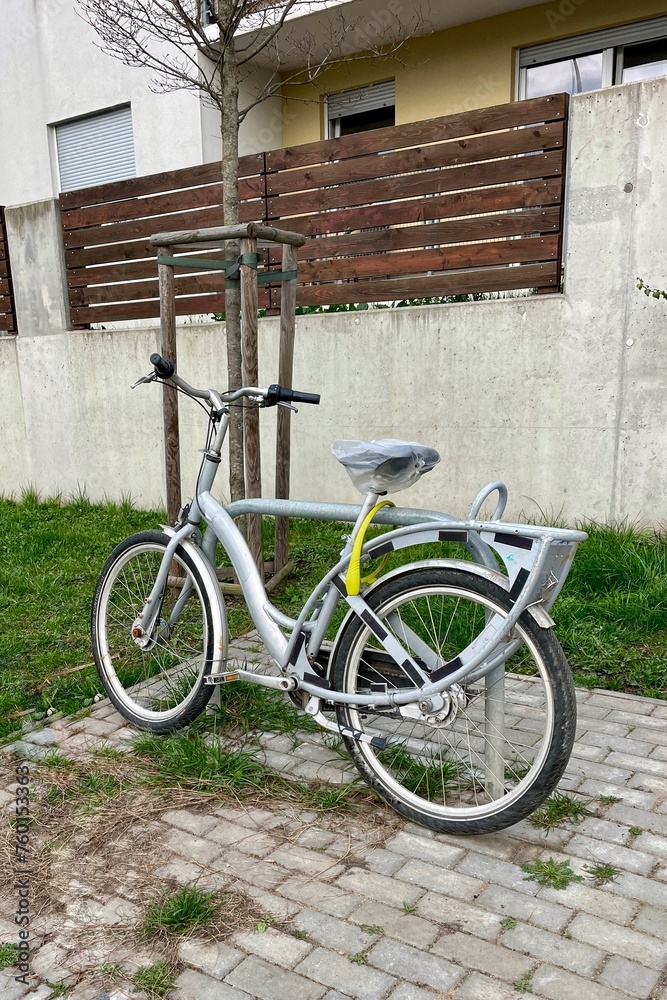 A bicycle is parked on the street under the fence near the house.