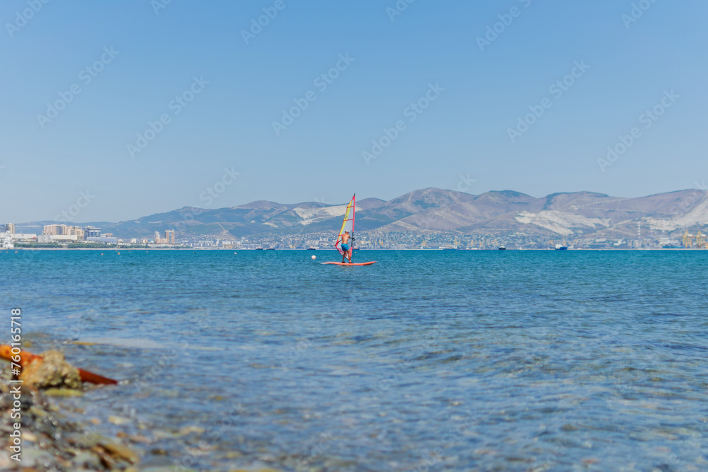 A man is engaged in windsurfing at sea, summer sea holidays, active recreation at sea