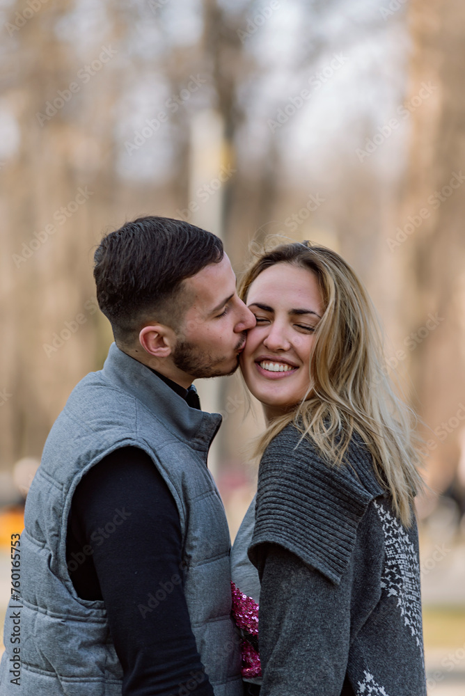 Happy smiling couple in love. Stylish man with a beard and a beautiful girl on the autumn sunny day kissing. Portrait of a happy young couple enjoying a day in the park together . Happy smiling couple in love. Stylish man with a beard and a beautiful girl on the autumn sunny day kissing. Portrait of a happy young couple enjoying a day in the park together .