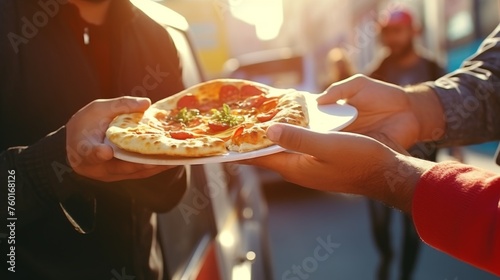 A hand delivering a cheesy slice of pizza garnished with basil in an outdoor setting, portraying sharing and street food culture