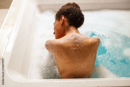 Woman happily bathing in waterfilled bathtub for leisure