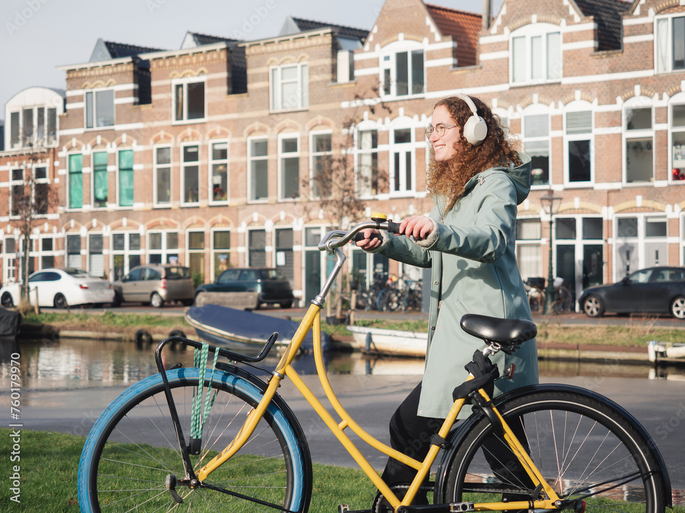 Fototapeta premium Curly-Haired Woman Enjoying Sunny Day with Her Bike by Amsterdam Canal