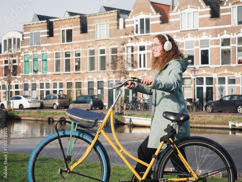 Curly-Haired Woman Enjoying Sunny Day with Her Bike by Amsterdam Canal