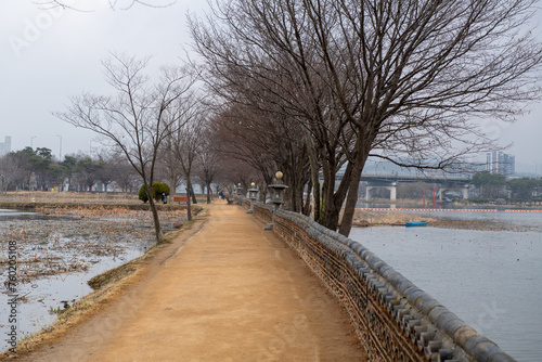 A quiet park's walking path, lake, and winter trees  © Kim Sehwan