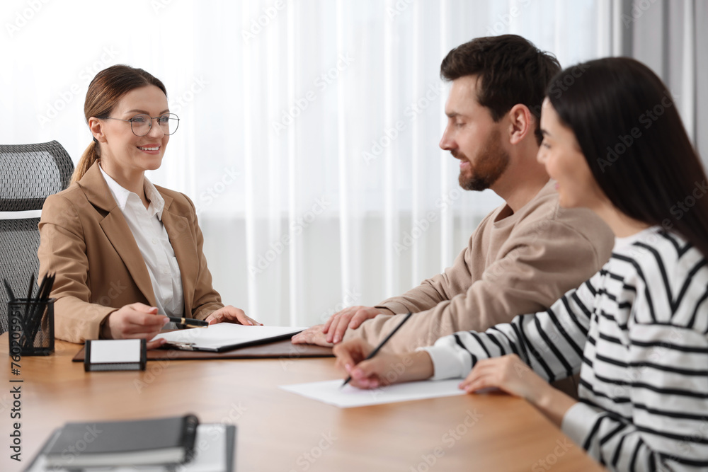 Couple signing document while having meeting with lawyer in office Couple signing document while having meeting with lawyer in office