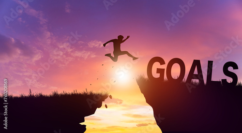 Silhouette man jumping form cliff to another mountain with Goals. Possible of Goals in business Concept. Copy space.
