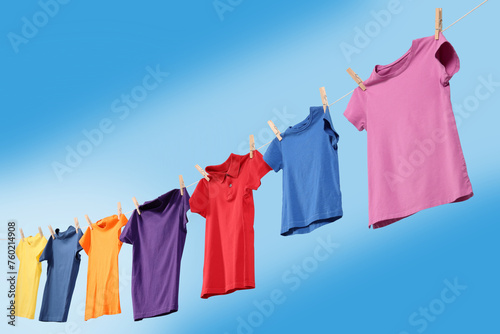 Colorful t-shirts drying on washing line against blue sky