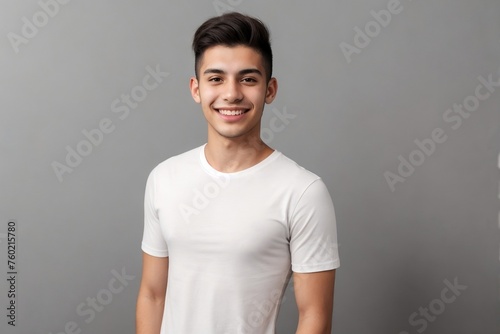 Young Brazilian man in a white shirt, smiling and looking at the camera, standing on a grey background with copy space. © PNG&Background Image