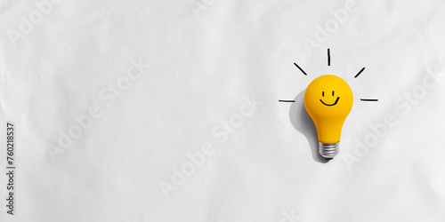 Yellow light bulb with happy face - flat lay photo