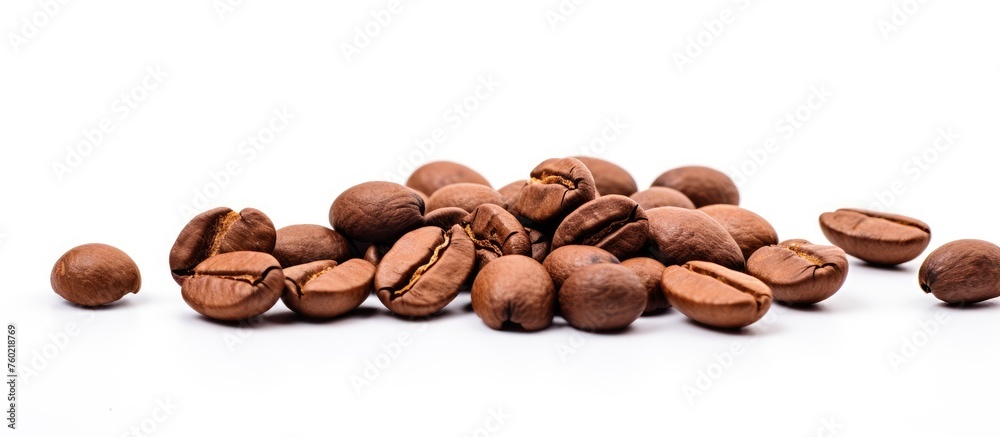 Naklejka premium Scattered coffee beans on a clean white background - aromatic drink ingredient concept