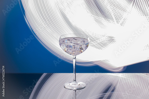 Close-up view of a drink with ice cubes in a glass, isolated on a blue-white background.