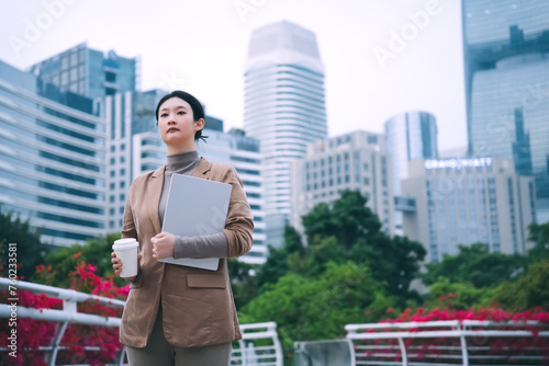 Confident Businesswoman Walking with Laptop and Coffee