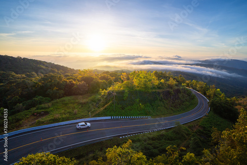 Aerial view of national park Inthanon, cars driving on curved, zigzag curve road or street on mountain hill with green natural forest trees in rural area of Chiang Mai, Thailand.