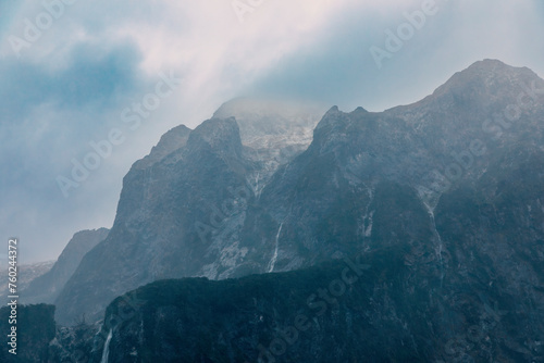Photograph of mountains in clouds and mist viewed from the water in Milford Sound in Fiordland National Park on the South Island of New Zealand