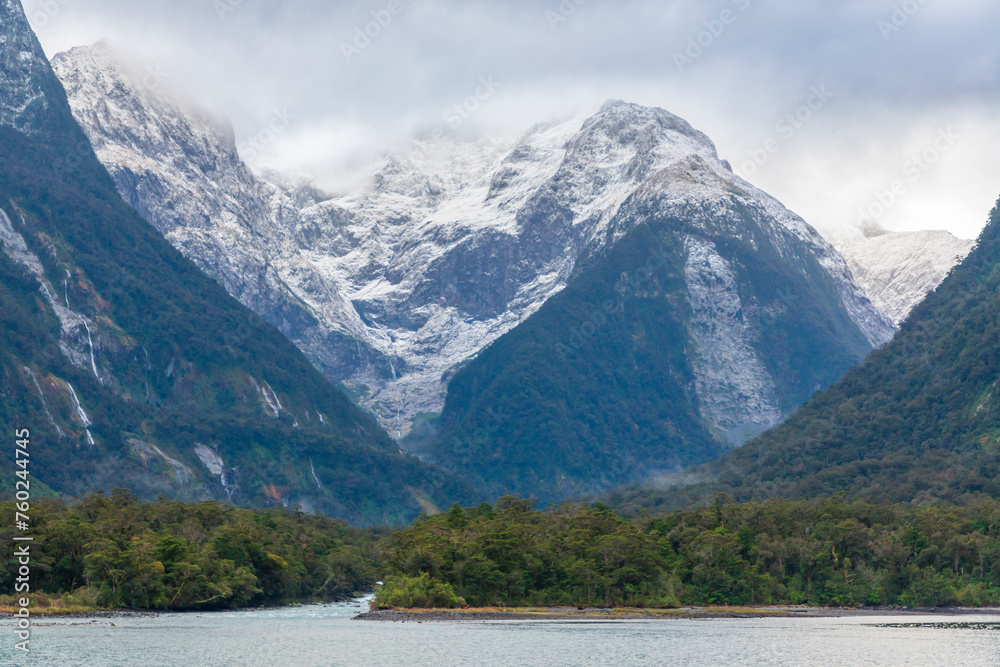 Photograph of mountains in clouds and mist viewed from the water in Milford Sound in Fiordland National Park on the South Island of New Zealand Photograph of mountains in clouds and mist viewed from the water in Milford Sound in Fiordland National Park on the South Island of New Zealand