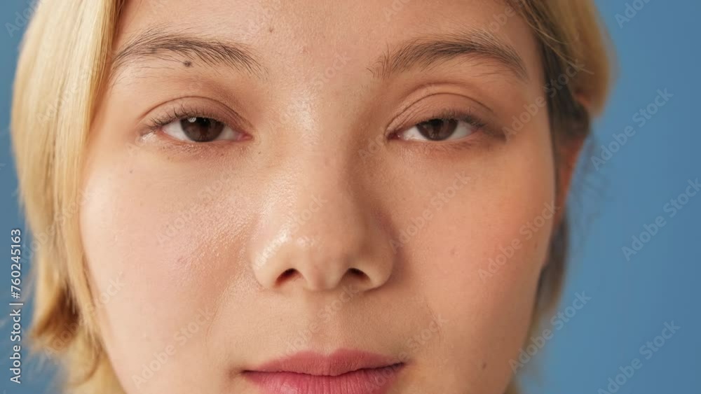 Portrait woman opens eyes and looks at camera isolated on blue backgroundin studio Portrait woman opens eyes and looks at camera isolated on blue backgroundin studio