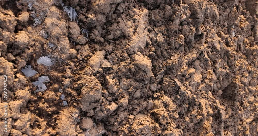 frozen soil in a field in winter , frozen land in an agricultural plowed field in sunny weather frozen soil in a field in winter , frozen land in an agricultural plowed field in sunny weather