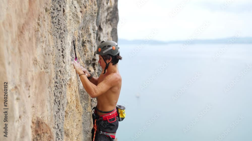 Young Asian man climber with safety hanging rope climbing on rocky mountain at tropical beach island. Healthy people enjoy outdoor active lifestyle extreme sport climbing on summer holiday vacation. Young Asian man climber with safety hanging rope climbing on rocky mountain at tropical beach island. Healthy people enjoy outdoor active lifestyle extreme sport climbing on summer holiday vacation.