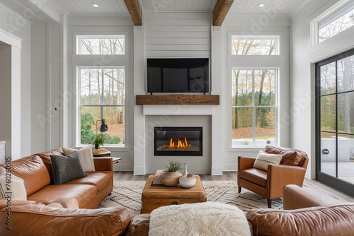 Simple living room in a modern farmhouse with little decoration Brown leather sofa and armchairs with a gas fireplace with a raw edged wooden mantel. photo