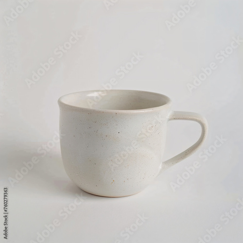 a white coffee cup with a handle on a white surface