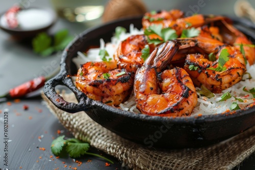 Grilled spicy shrimp served with rice in skillet - Grilled shrimp marinated in spicy sauce served on a bed of rice in a rustic skillet, garnished with herbs and spices photo