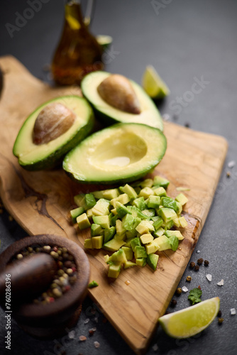 Halved green avocado fruit on wooden cutting board at domestic kitchen