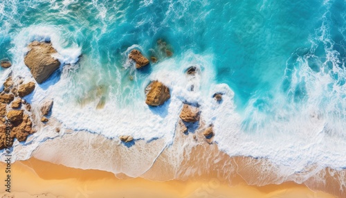 Aerial view of a paradise beach where the sea waves break on the shore. Top view of a beautiful sandy coast with turquoise blue water and white foam on sunny day. Summertime, traveling, vacation.