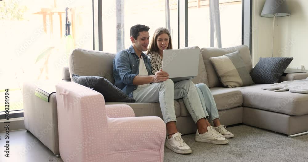 Couple sit on sofa with laptop in modern living room, make order, buy goods, select gifts on holiday, planning travel, enjoy easy and comfortable electronic shopping. Marketplace, e-shopping clients Couple sit on sofa with laptop in modern living room, make order, buy goods, select gifts on holiday, planning travel, enjoy easy and comfortable electronic shopping. Marketplace, e-shopping clients