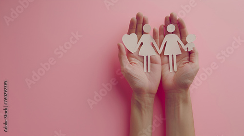 Cropped photo of mother, father, and child clutching family paper cutouts in their hands, isolated on a pink background. Cardboard figures of parents and children holding hands.International familyDay photo