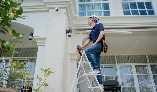 A technician installs a CCTV camera on the facade of a residential building.