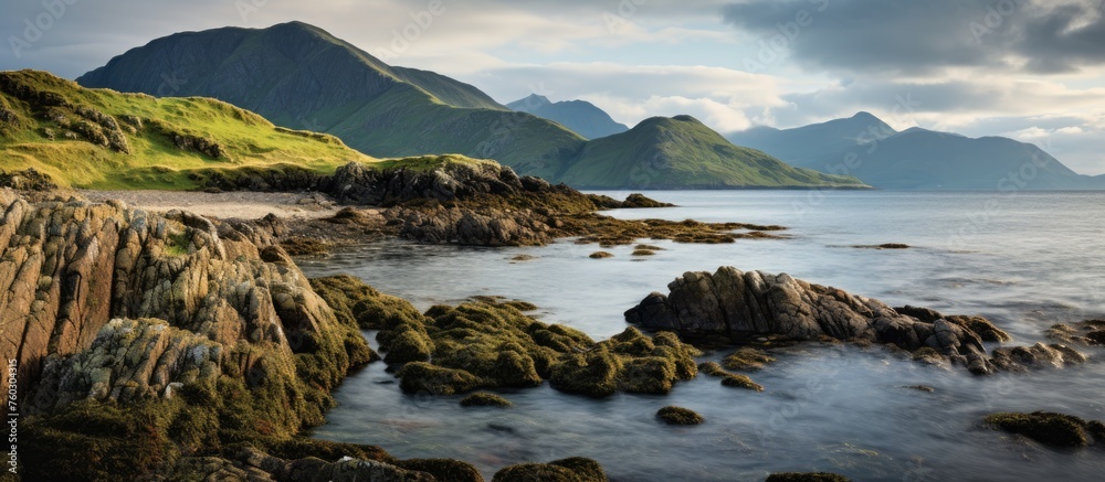 Serene Coastal Landscape: Rocky Beach Embraced by Majestic Mountains in the Distance