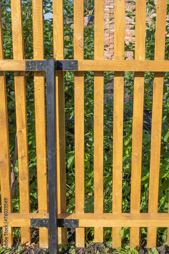 Close-up of a new wooden picket fence in the backyard of a country house  summer sunny day  vertical photo